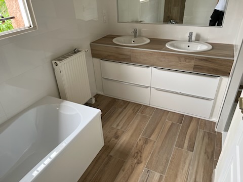 Rénovation de salle de bain à Eaunes avec baignoire, double vasque et carrelage effet bois